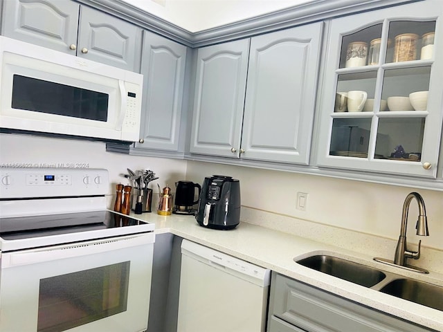 kitchen with gray cabinetry, sink, and white appliances