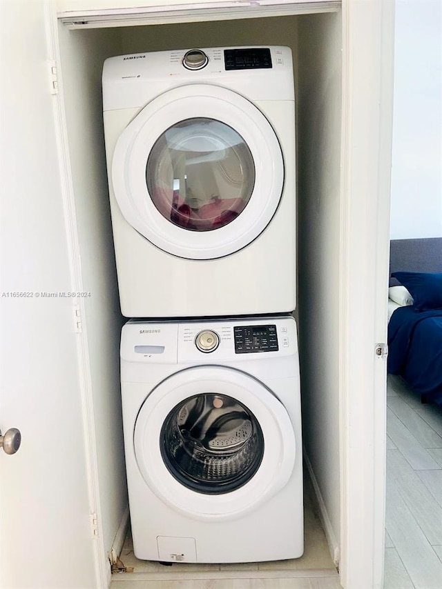 laundry room with stacked washer and dryer and light hardwood / wood-style floors