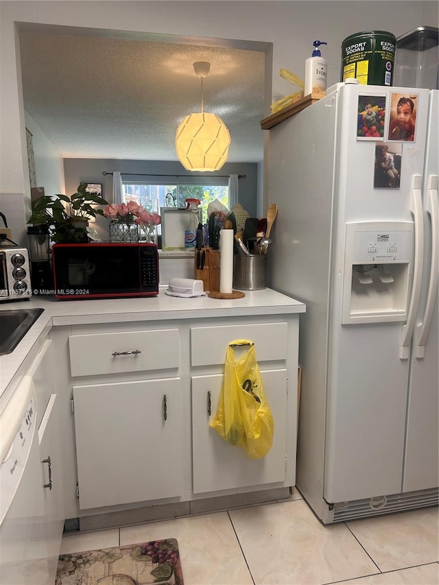 kitchen featuring white appliances, a textured ceiling, and light tile patterned floors