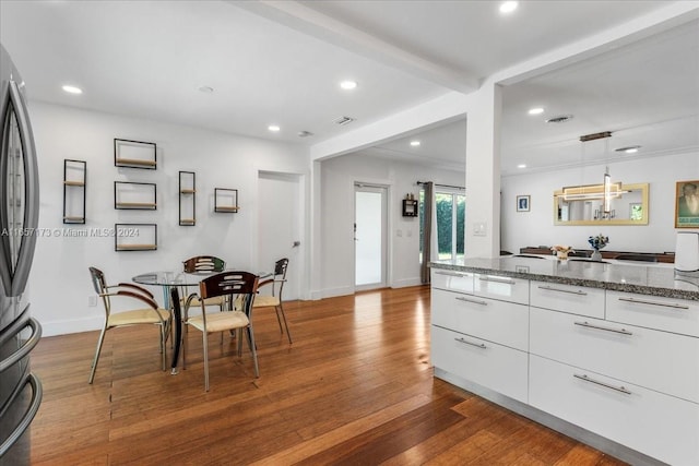 kitchen featuring beamed ceiling, stainless steel fridge, white cabinetry, light hardwood / wood-style flooring, and hanging light fixtures