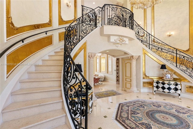 staircase with a high ceiling and decorative columns