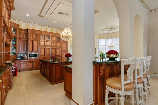 kitchen with a kitchen island with sink, pendant lighting, a chandelier, sink, and appliances with stainless steel finishes