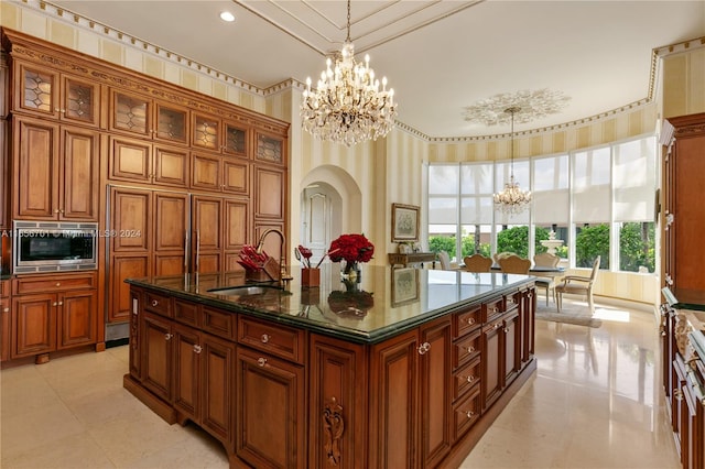 kitchen with a healthy amount of sunlight, an island with sink, a notable chandelier, and sink