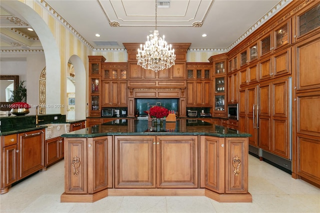 kitchen with dark stone counters, built in appliances, a chandelier, a kitchen island, and kitchen peninsula