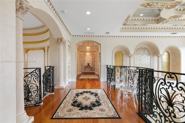 hallway featuring hardwood / wood-style floors, decorative columns, and a raised ceiling