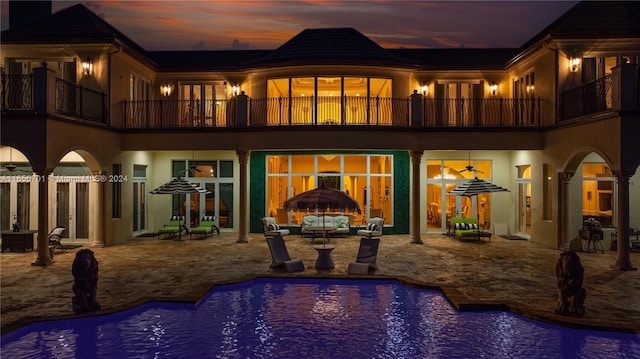 pool at dusk with a patio area