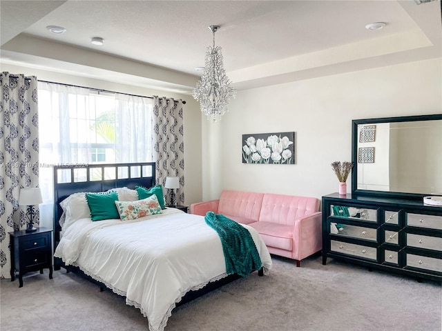 carpeted bedroom featuring a tray ceiling and a chandelier