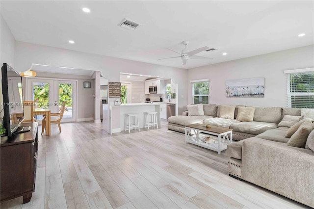 living room with french doors, ceiling fan, sink, and light hardwood / wood-style floors