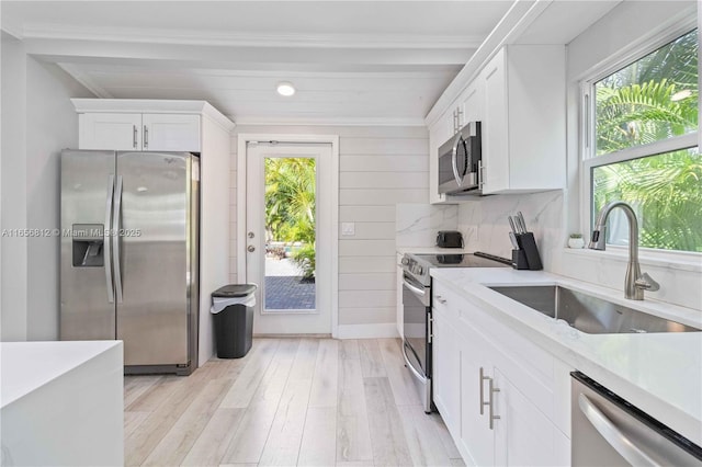 kitchen featuring a healthy amount of sunlight, appliances with stainless steel finishes, sink, and white cabinets