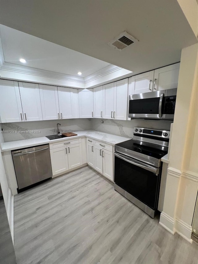 kitchen with light wood-type flooring, white cabinets, appliances with stainless steel finishes, and sink