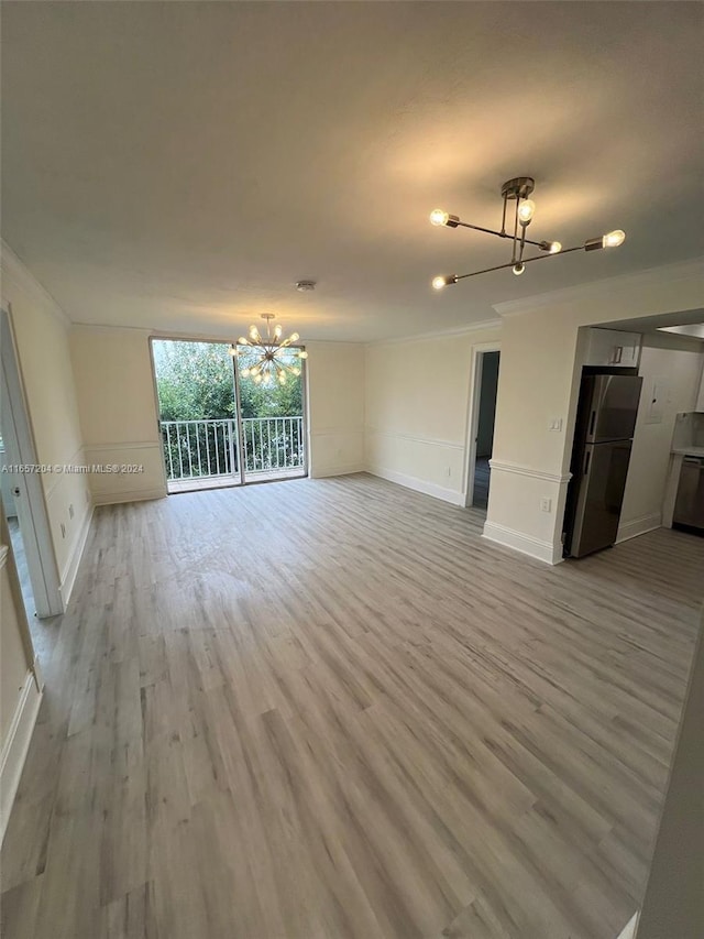 spare room featuring crown molding, hardwood / wood-style floors, and a notable chandelier