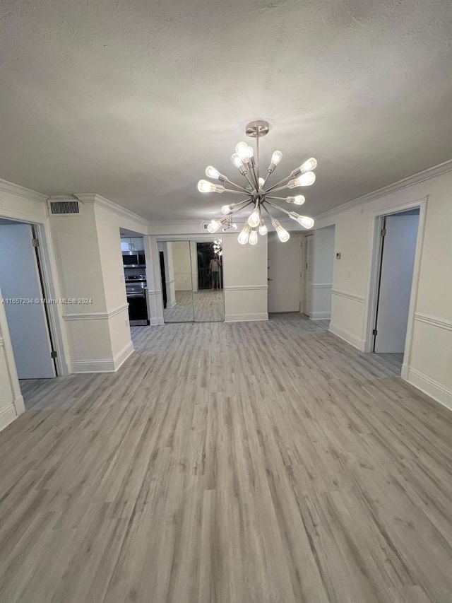 unfurnished living room featuring ornamental molding, an inviting chandelier, wood-type flooring, and a textured ceiling