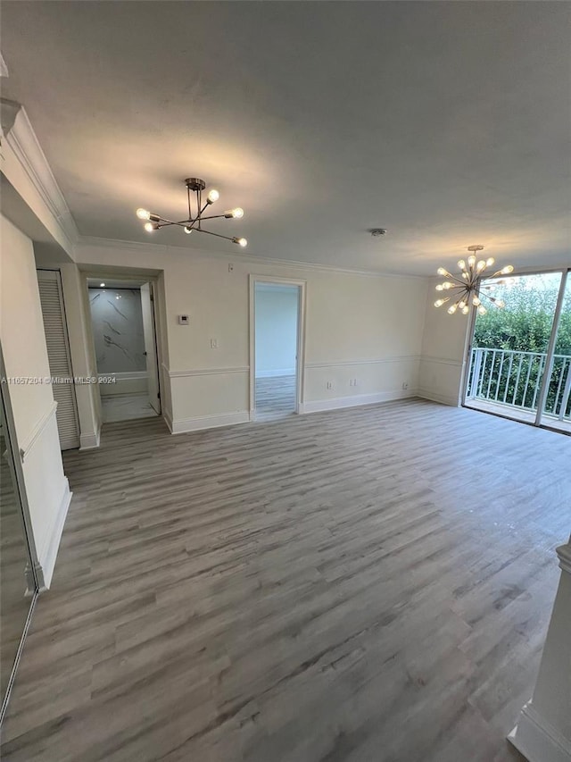 unfurnished living room featuring ornamental molding, wood-type flooring, and a notable chandelier