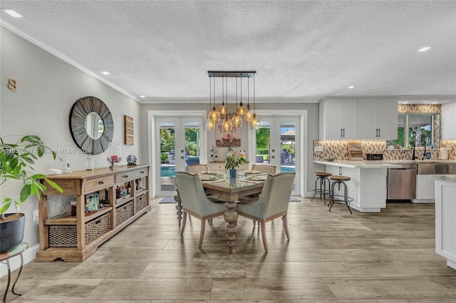 dining space with crown molding, french doors, a textured ceiling, and light hardwood / wood-style flooring