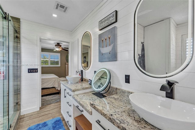 bathroom featuring an enclosed shower, hardwood / wood-style floors, wood walls, ceiling fan, and vanity