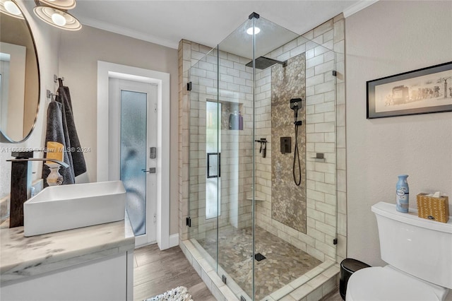 bathroom with toilet, hardwood / wood-style floors, a shower with door, ornamental molding, and vanity