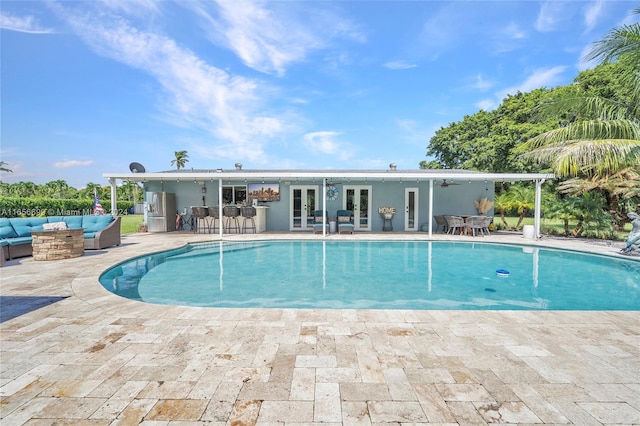 view of pool featuring french doors, an outdoor living space, a patio area, and exterior bar