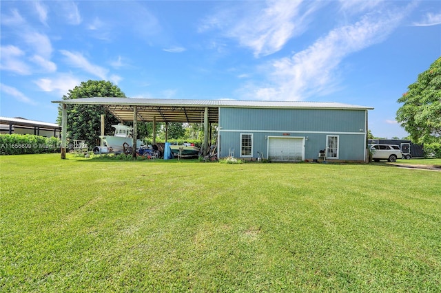 rear view of property featuring a lawn, a carport, and a garage