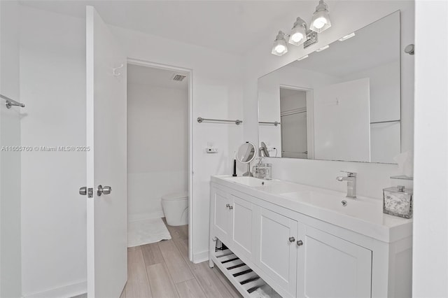 bathroom with visible vents, a sink, toilet, and double vanity