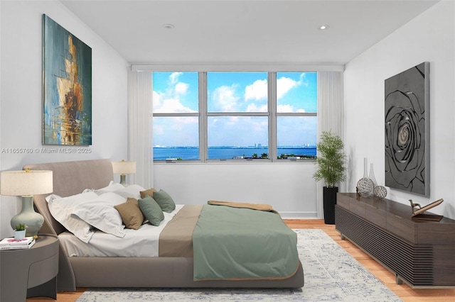 bedroom featuring light wood finished floors and a water view