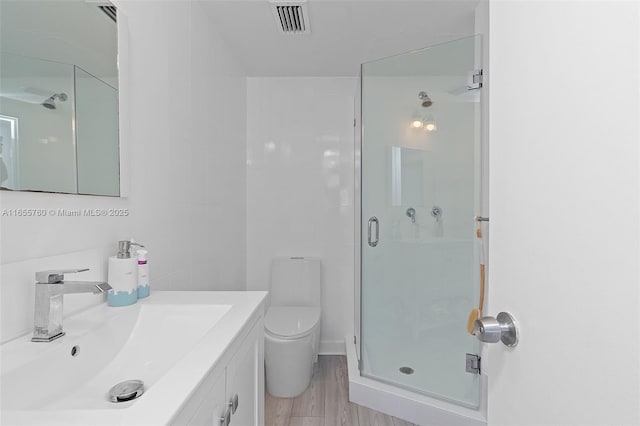 bathroom featuring a stall shower, visible vents, vanity, and toilet