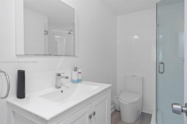 full bathroom with toilet, wood finished floors, vanity, tile walls, and a shower stall