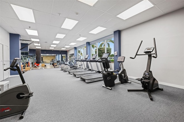 gym featuring a paneled ceiling and baseboards