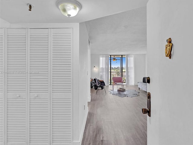 hall with a textured ceiling, hardwood / wood-style floors, and a wall of windows