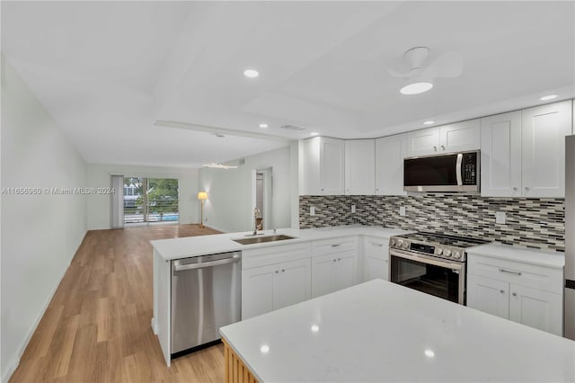 kitchen with light hardwood / wood-style flooring, appliances with stainless steel finishes, tasteful backsplash, kitchen peninsula, and sink