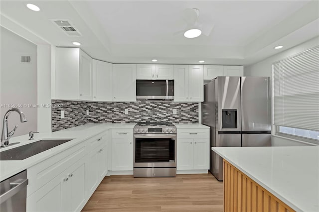 kitchen featuring white cabinets, appliances with stainless steel finishes, sink, and light hardwood / wood-style flooring