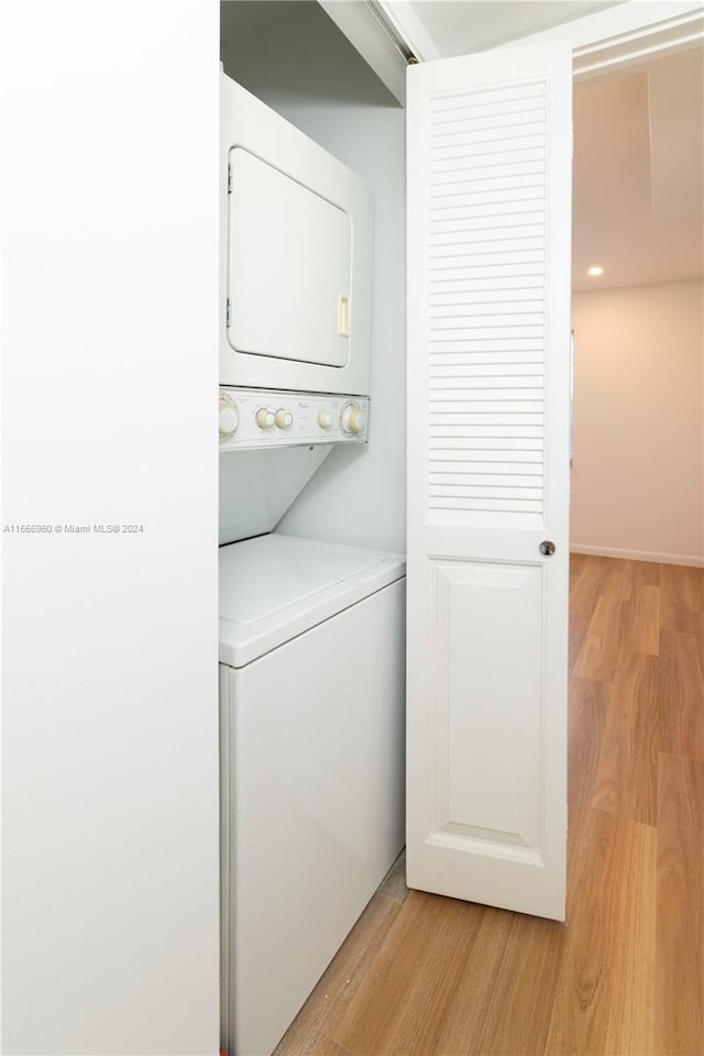 laundry room featuring light wood-type flooring and stacked washer and clothes dryer