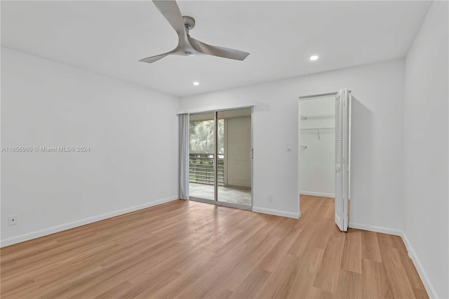 unfurnished bedroom with a walk in closet, a closet, light hardwood / wood-style floors, access to exterior, and ceiling fan