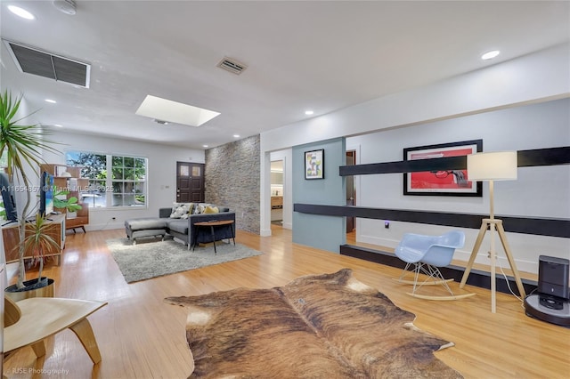 living room with light hardwood / wood-style flooring and a skylight