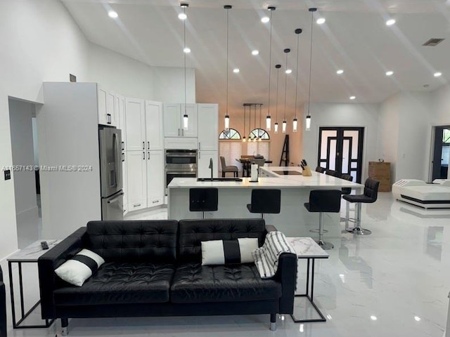 interior space featuring white cabinets, decorative light fixtures, stainless steel appliances, a large island, and a breakfast bar