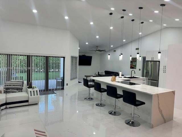 kitchen with decorative light fixtures, light stone countertops, white cabinetry, stainless steel fridge, and a spacious island