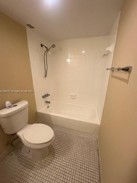 bathroom with tile patterned floors, tiled shower / bath, and toilet