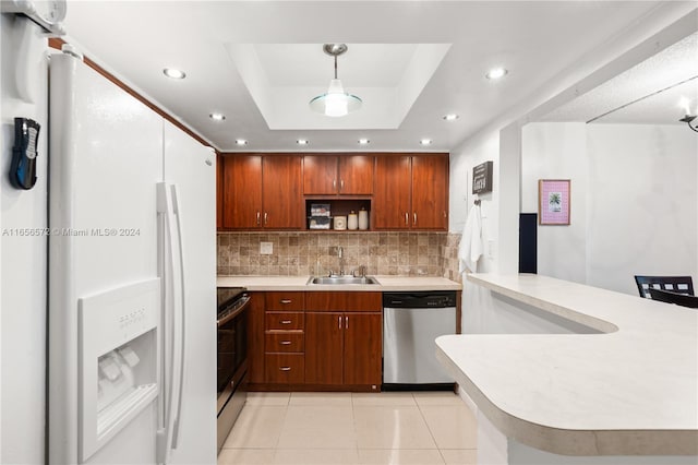 kitchen featuring white fridge with ice dispenser, sink, hanging light fixtures, a tray ceiling, and stainless steel dishwasher