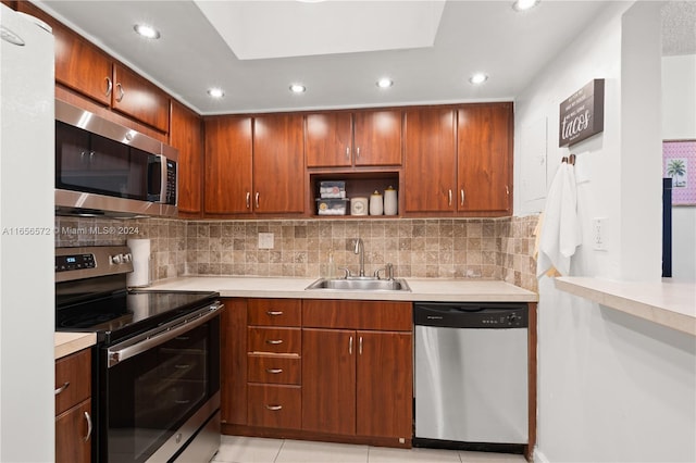 kitchen featuring appliances with stainless steel finishes, light tile patterned floors, sink, and decorative backsplash