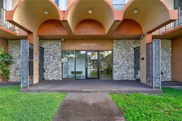 entrance to property with a balcony and a lawn