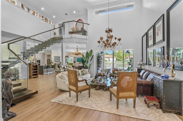 living room with ornamental molding, a high ceiling, a notable chandelier, and light hardwood / wood-style floors