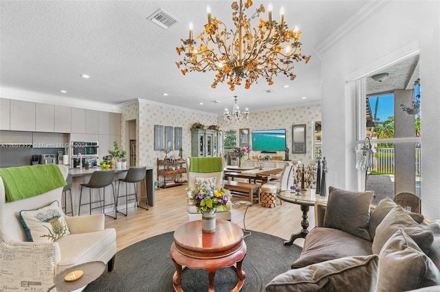 living room with crown molding, light hardwood / wood-style flooring, and an inviting chandelier