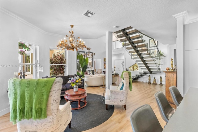 living room with crown molding, a chandelier, and light hardwood / wood-style floors