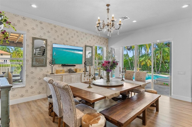 dining room with crown molding, a healthy amount of sunlight, an inviting chandelier, and light hardwood / wood-style floors