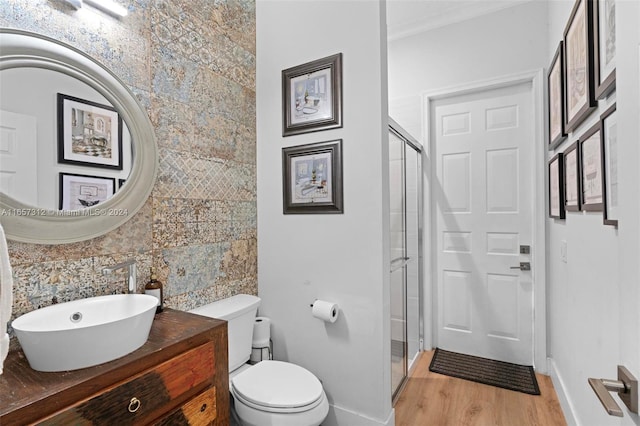 bathroom featuring backsplash, a shower with door, hardwood / wood-style flooring, toilet, and vanity