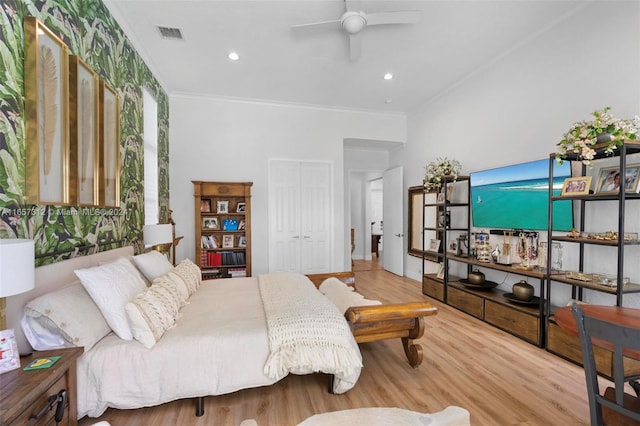 bedroom featuring crown molding, light hardwood / wood-style flooring, ceiling fan, and a closet