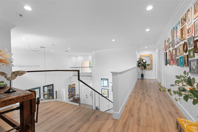 corridor with light wood-type flooring and crown molding