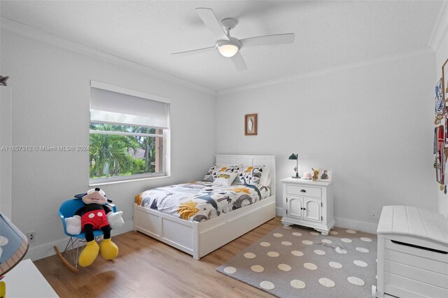 bedroom featuring light hardwood / wood-style flooring, ceiling fan, and ornamental molding