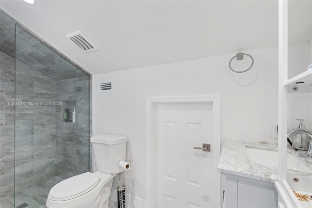 bathroom with vanity, toilet, and a tile shower