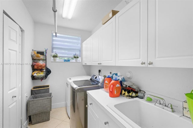 clothes washing area with light tile patterned floors, cabinets, sink, and washer and clothes dryer