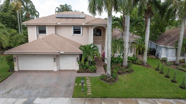 mediterranean / spanish house featuring solar panels, a front yard, and a garage